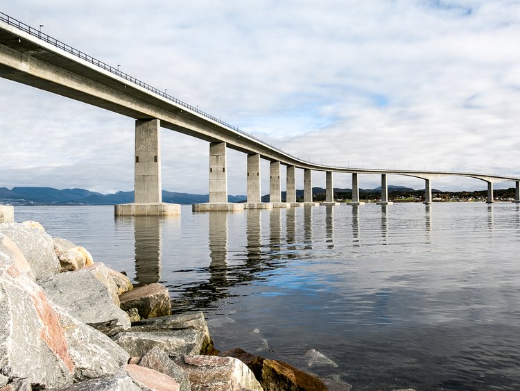 Photo: bridge crossing a fjord in a significant turn, viewed from the shore