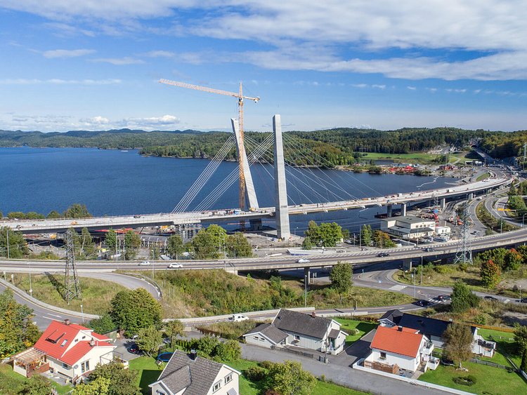 Photo: aerial view of Farris Bridge traversing the edge of Farris Lake and a railway line, a rural settlement area in the foreground, panorama of lake and woods in the background.